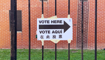 Multilingual voting directional sign in English, Spanish, and Chinese posted at a polling location, showing language accessibility in elections