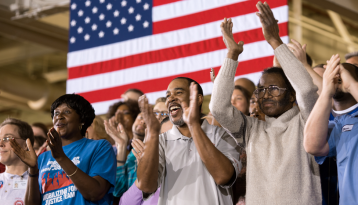 Crowd clapping with American flag in background