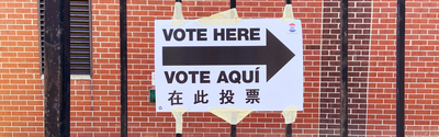 Multilingual voting directional sign in English, Spanish, and Chinese posted at a polling location, showing language accessibility in elections