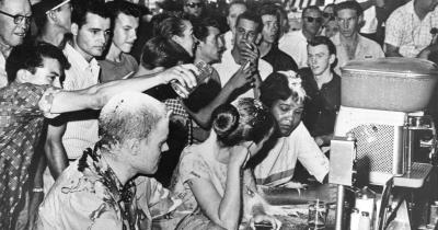 Jackson, MS, Woolworth Lunch Counter Sit-In —white men pouring sugar on the heads of protestors and a woman of color