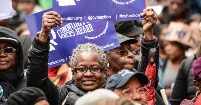 Woman holding poster above her head at Community Voices Heard rally