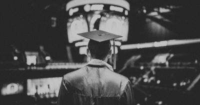 Graduate wearing cap and gown from behind in black and white