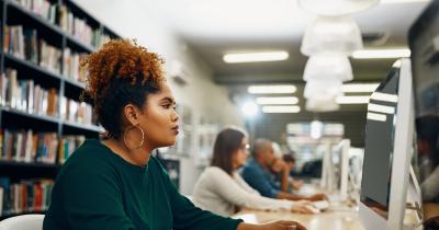 Black woman working at computer in college library