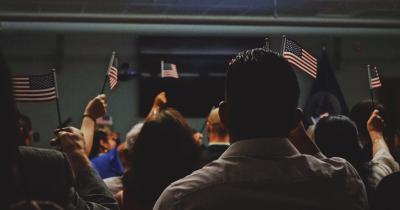 Group of people raising American flags at a naturalization ceremony