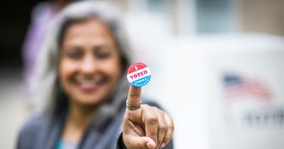 "I Voted Today" sticker on the pointer finger of a Latina woman.