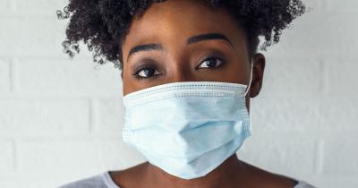 Black woman with curly hair wearing mask