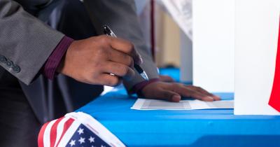 Black voter hovering over a former with a pen
