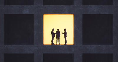 Backlit men standing in an office building window, talking