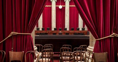 View of Supreme Court justices seats from the gallery with seats and a red curtain in foreground