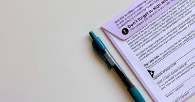 Pen next to voter registration form and envelope