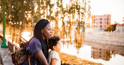 Black mother and daughter looking at the city river