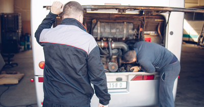Bus manufacturer workers under the hood of a bus