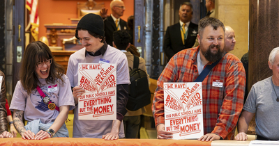 A group of people is standing together in an indoor setting, holding signs that read, "We have the resources to make everything we love resilient." The signs also feature the logos for MN350 and 100 Percent Campaign. 
