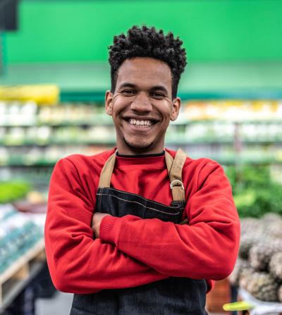 Smiling black retail worker in front of groceries