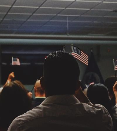 Group of people raising American flags at a naturalization ceremony