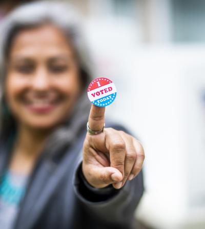 "I Voted Today" sticker on the pointer finger of a Latina woman.