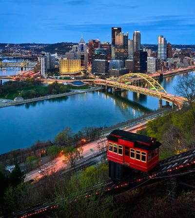 Pittsburgh skyline at dusk from hillside overlooking river