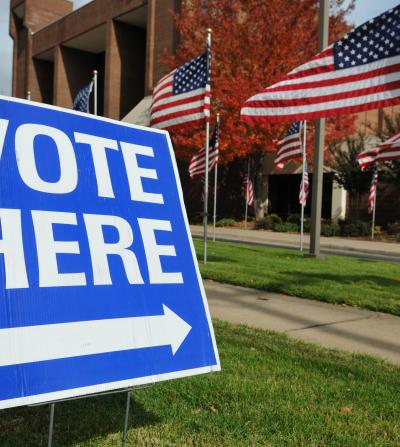 "Vote Here" sign in the grass in front of a polling station