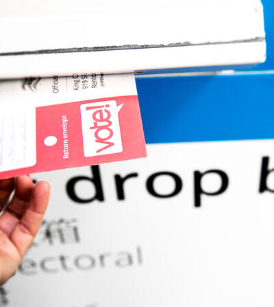 White hand putting ballot in mailbox