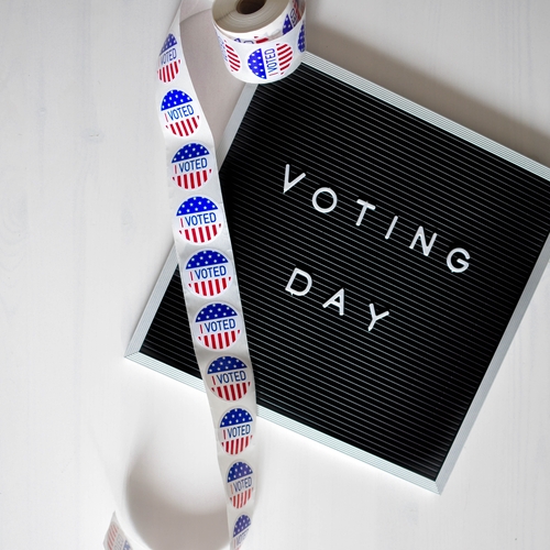 I Voted sticker roll over Voting Day sign