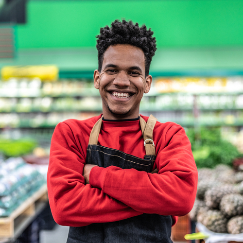 Smiling black retail worker in front of groceries