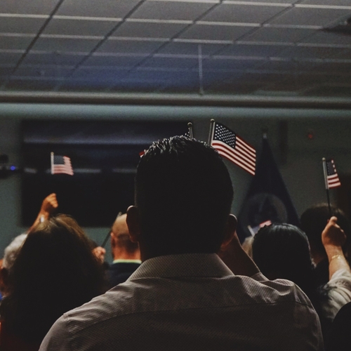 Group of people raising American flags at a naturalization ceremony