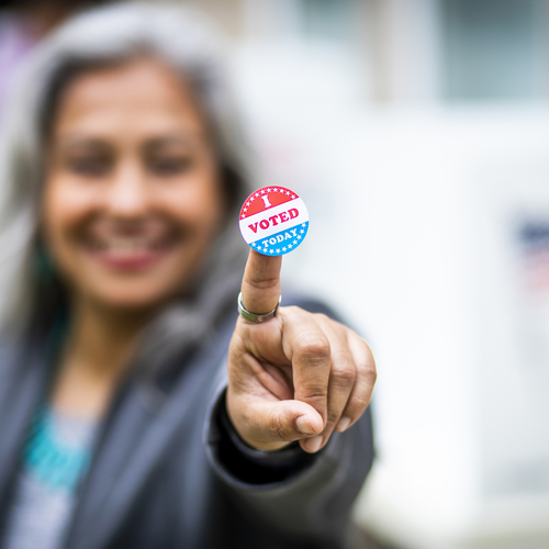 "I Voted Today" sticker on the pointer finger of a Latina woman.