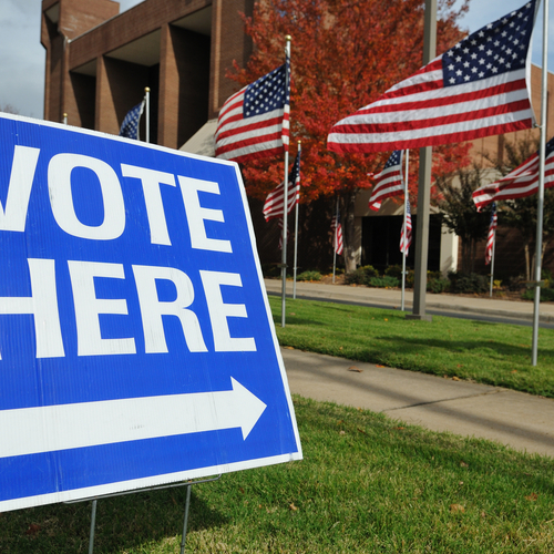 "Vote Here" sign in the grass in front of a polling station