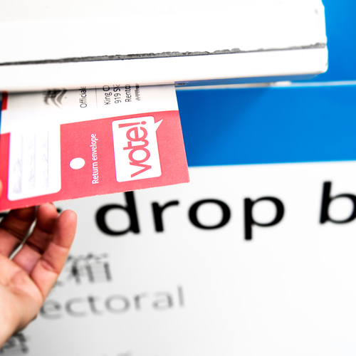 White hand putting ballot in mailbox