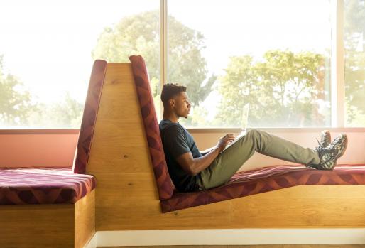 Black student reclined and working on computer