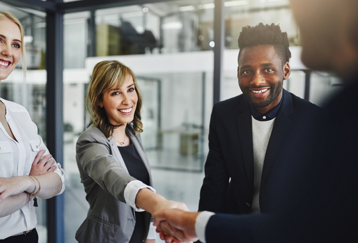 Smiling white woman and Black man shaking the hand of a job applicant