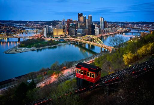 Pittsburgh skyline at dusk from hillside overlooking river