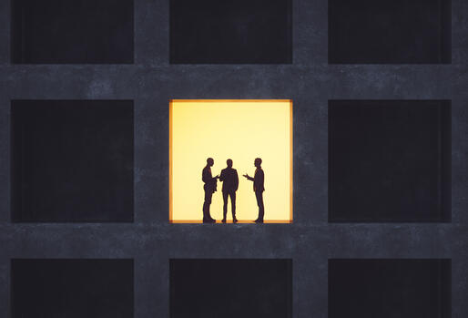 Backlit men standing in an office building window, talking