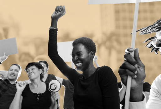 A person smiling broadly and raising their arm in a gesture of triumph at a protest or rally, surrounded by other participants, some holding signs and a megaphone. The background features an abstract cityscape.