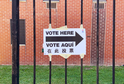 Multilingual voting directional sign in English, Spanish, and Chinese posted at a polling location, showing language accessibility in elections