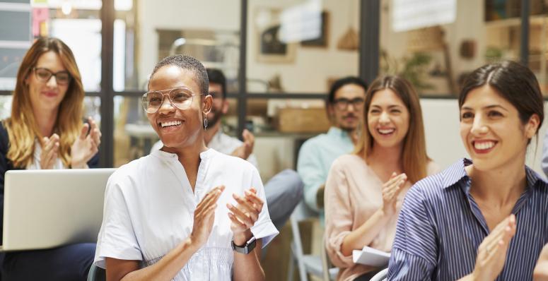 Multiracial room applauding and laughing at speaker off frame