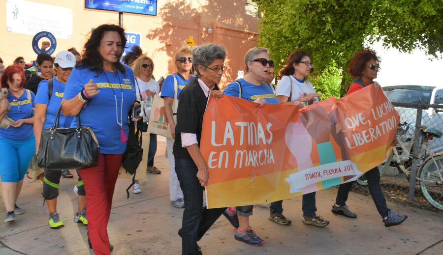 Latinas marching with a banner for love and liberation